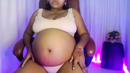 Penti sutyenli hamile bayan göbek oynuyor ve su içiyor.