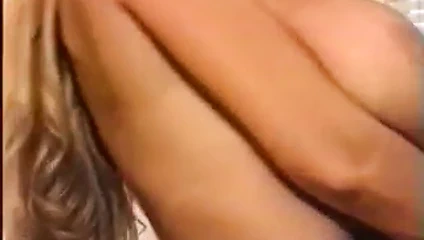 Büyük memeli sarışın soyunuyor ve kanepede göğüsleri ile oynuyor