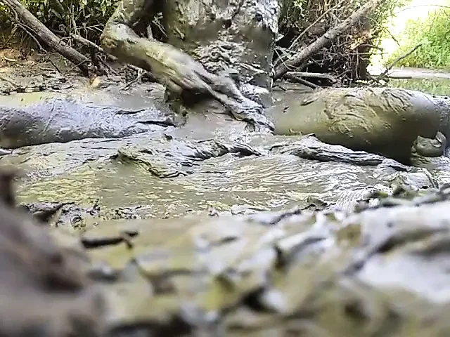 Çamur deliğinde oynayan çıplak adam