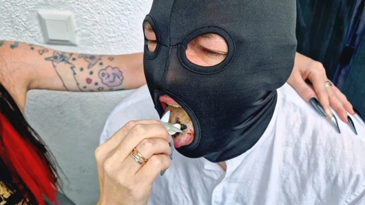 Dominatrix balkonda sigara içiyor ve kül tablası olarak bir adamı kullanıyor