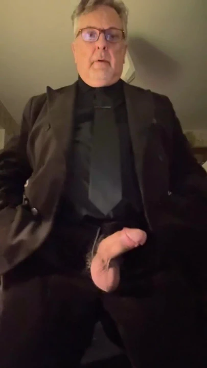 Koyu kahverengi takım elbiseli büyük yarak gösteriyor