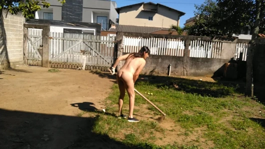 İnsanlar sokakta yürürken ev hanımı bahçede çıplak çalışıyor