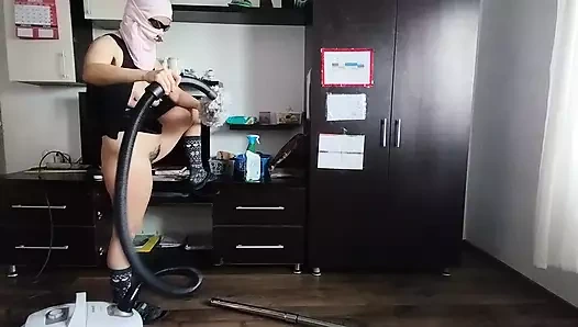 Bir amatör evi çıplak, elektrikli süpürgeyle temizler.