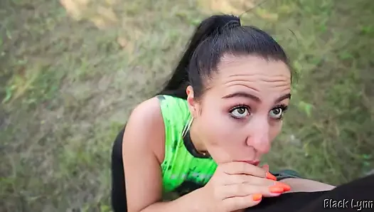 Bakış açısı spor giyimli at kuyruklu esmer yarak emiyor ve açık havada yüze boşalma