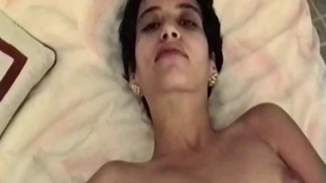 Esmer kadın yatakta soyunuyor ve soyunuyor