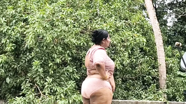 Dolgun hatlı bir kadın beyaz etek ve pembe üstle soyunup çıplak halde dışarı çıkıyor.