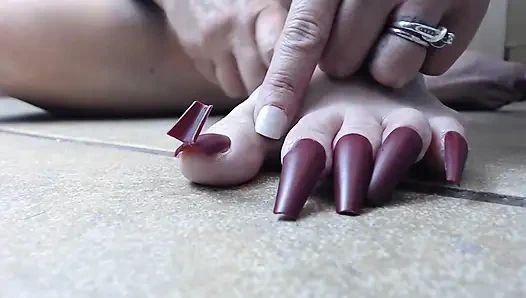 Uzun ayak tırnaklarını kırpıyor