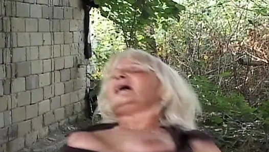 Yaşlı kadın dışarıda amıyla oynuyor ve dövmeli bir adamdan sert anal sikişiyor