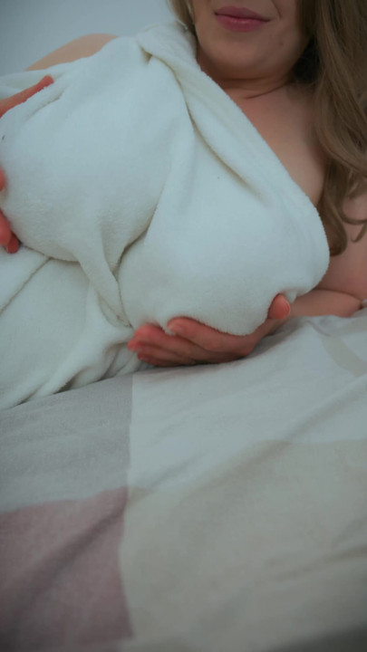 Orta yaşlı seksi kadın beyaz battaniye içinde kraliçe gibi davranıyor. Biri ona o göğüslerin güzel olduğunu söylemeli