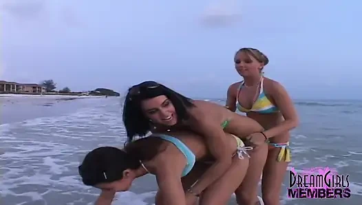Üç ateşli kız halka açık bir plajda sevişiyor ve üstsüz oluyor