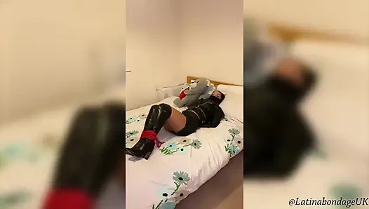 Latina em botas de couro e roupa de couro completa amarrada apertada e engasgada