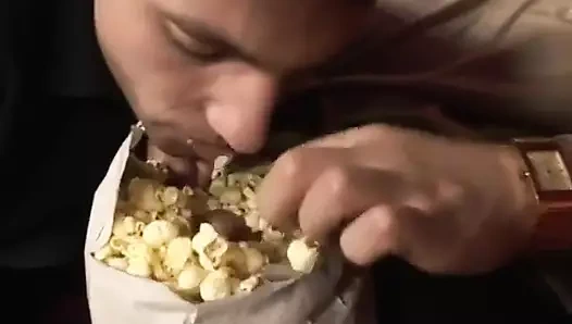 Kısa saçlı kaslı adam genç meraklı adam James Jones'a pop mısırını ve büyük etini tatmaya davet ediyor