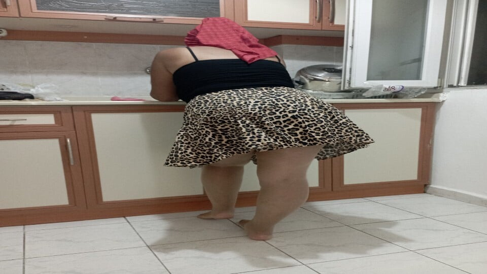 Başörtüsü takan dul bir kadın bulaşık yıkıyor.
