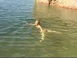 Sevimli genç esmer su kenarında soyunur ve sıska dalmaya gider