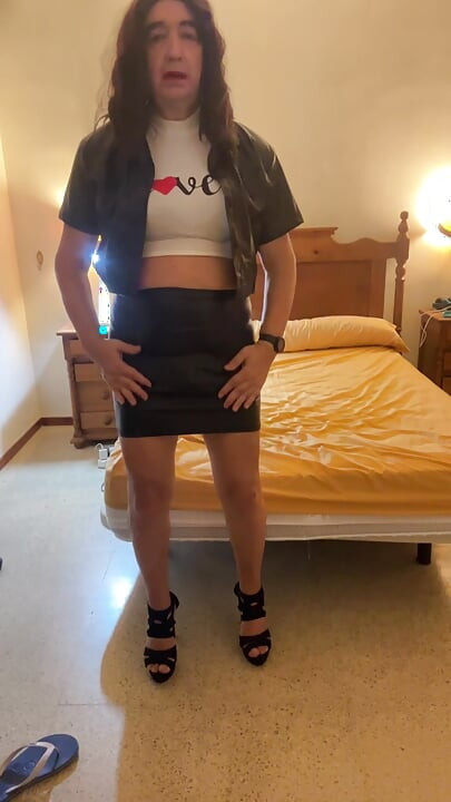 Beautiful and sexy Spanish trans girl masturbates in a tight miniskirt and black latex jacket in the bedroom, wearing high heels