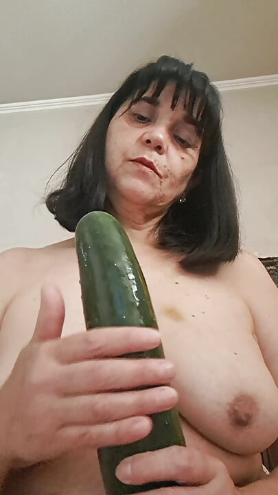 Orta yaşlı seksi kadın göğüsleri ve salatalık ile oynuyor, diliyle ıslatıyor