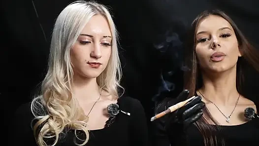 Siyah kıyafetli iki kadın yavaş duman ve eğlenceli etkileşimle bir sigara paylaşıyor