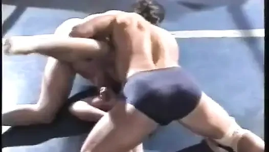 Mavi kısa boylu adam pembeli adamla güreşiyor