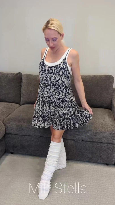 Elbise içinde çömele çoraplarını ikiye katlıyor