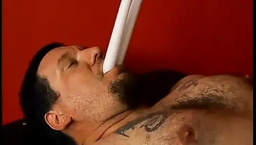 Latex-clad hottie torments a hairy guy with tats