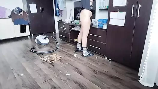 Amatör evli kadın yatak odasını elektrikli süpürgeyle temiziyor.
