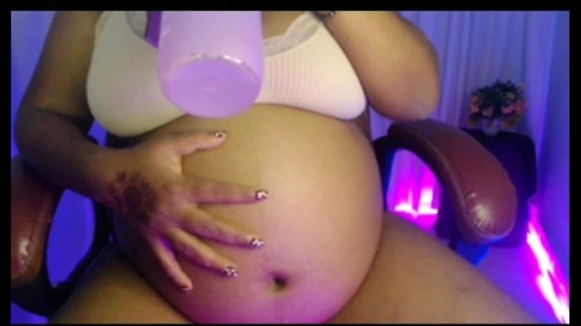 Pregnant lady in penty bra with playing belly and drinking water.