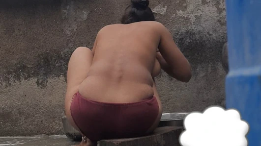 Açık evin dışındaki avludaki hamamda, üvey kız kardeş kırmızı taytla banyo yapıyor, tüm kıyafetler açık