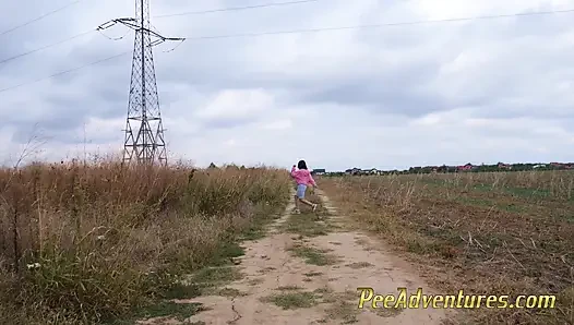 Hipster girl with a hoodie pee trough her jeans and pee next to the wheel of the car