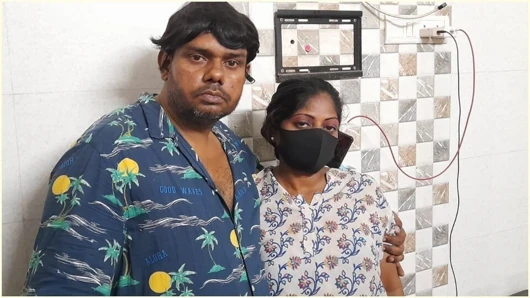The image features tw indoors The man is on the left, wearing a blue shirt with a