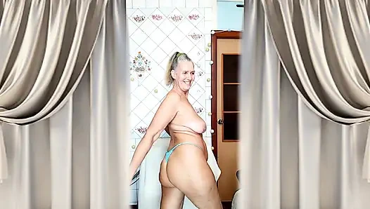 A mature blonde in a knitted dress shows off her curves in a home environment.