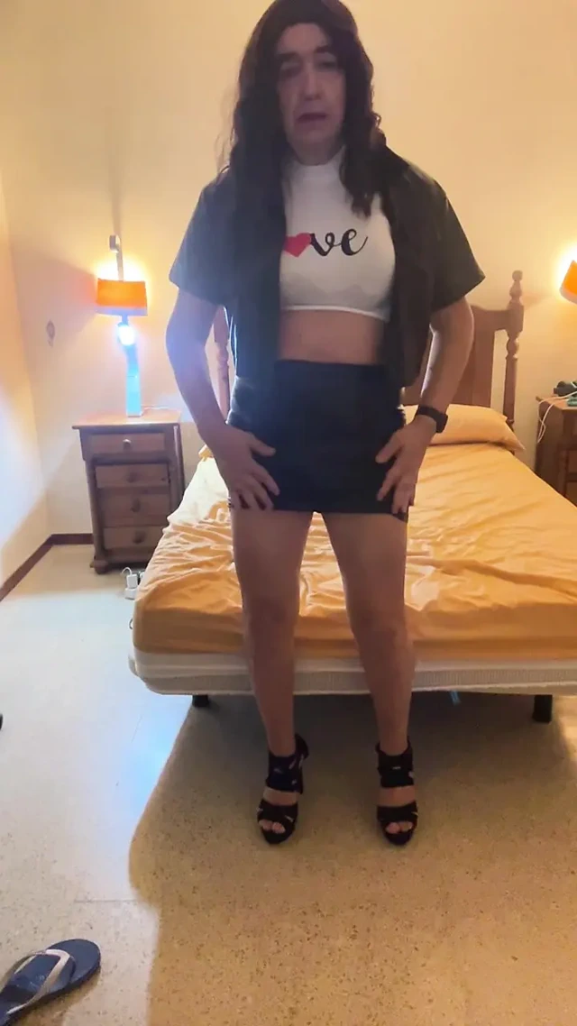 Beautiful and sexy Spanish trans girl masturbates in a tight miniskirt and black latex jacket in the bedroom, wearing high heels