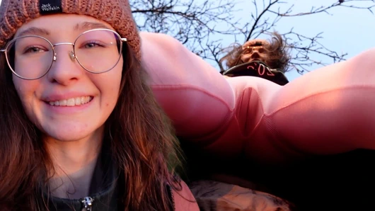 Sıska kız kırmızı sportleggins içinde açık havada am frikiği gösteriyor