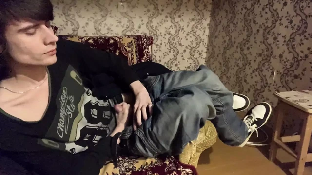 A boy in sneakers masturbates in the dark on an armchair