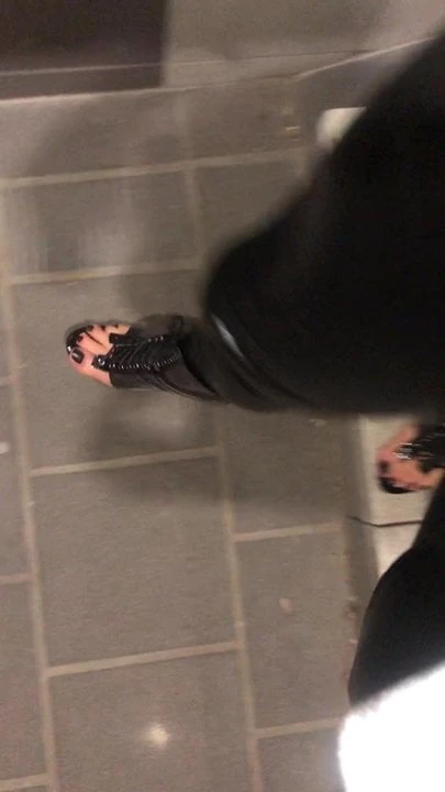 Tren istasyonunda lateks kedi tulumu ve açık topuklu ayakkabılar