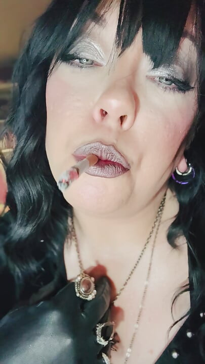 Siyah saçlı gotik sigara içiyor - iri güzel kadın Tina Snua deri eldivenler ve mücevherlerle sigara içiyor