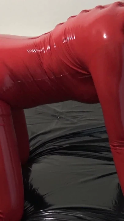 Lateks maskeli ve şeffaf yüzlü kırmızı lateks catsuit ile fotoğraf çekimi.
