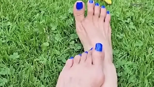 Melove mavi oje çimenlerde seksi ayaklarını gösteriyor