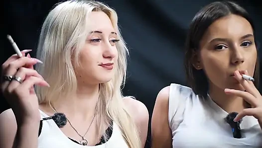 İki kız birlikte sigara paylaşıyor ve rahat bir stüdyo sahnesinde gülüyor