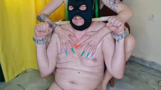 Uzun tırnak fetişi. Dominatrix Nika'nın yeni bir çok renkli manikürü var. Tırnaklarını ağrılı bir şekilde kölenin etine sokuyor.