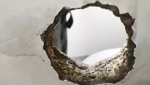 Gerçek duvar deliği. Halka açık toalett'te parıltılı delik