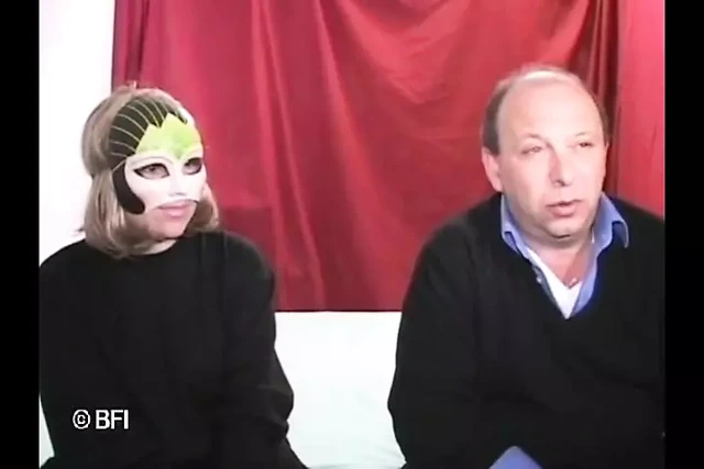 Milanlı maskeli kızıl saçlı bir grup erkeğe yarak emmeyi gösteriyor