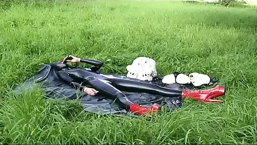 Lateksli fetiş köle yürüyor ve çimlerde dildo emiyor