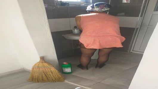 Tesettürlü olgun kadın seksi elbiseli evi temizliyor.