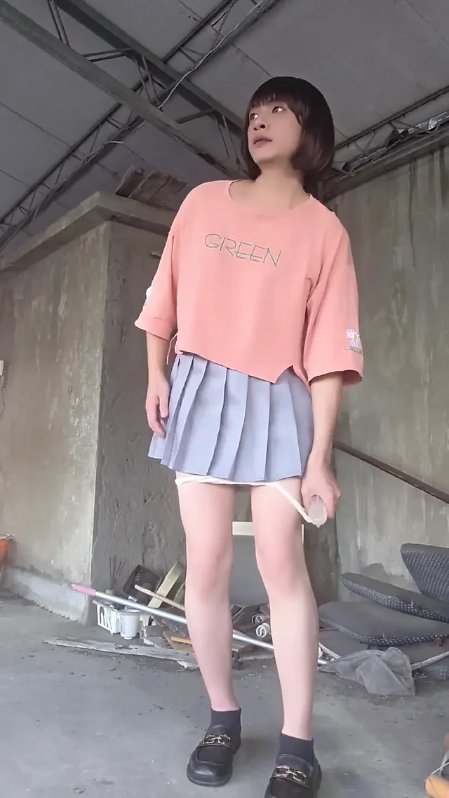 Beyaz iç çamaşırıyla eşleşen pleated bir etek ve terasa anal tıkaç takıyor