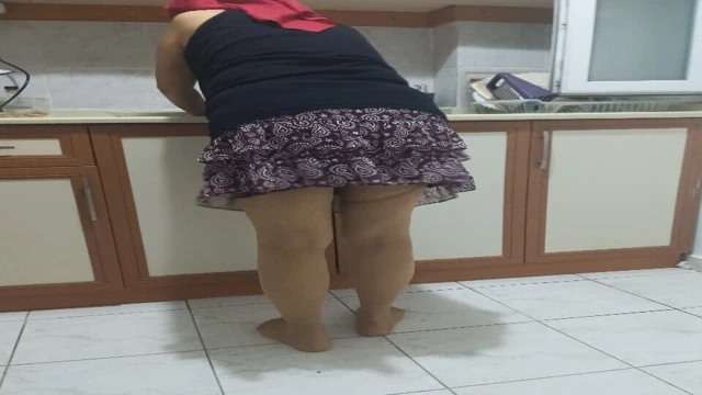 Külotlu çoraplı olgun kadın mutfakta ev işi yapıyor.