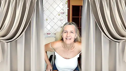 Mature grandmother with gray hair, figure and feet in the kitchen