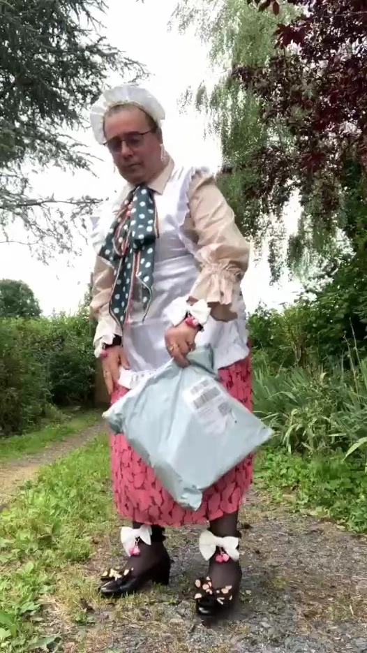 Posta kutusundan bir paket almaya gitmek için klasik hizmetçi kıyafeti içinde.