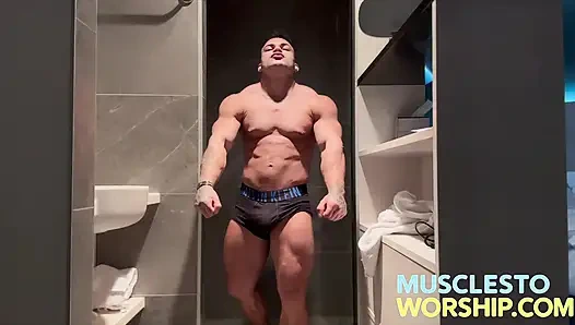 Genç alfa vücut geliştirmeci büyük kasları esnetiyor