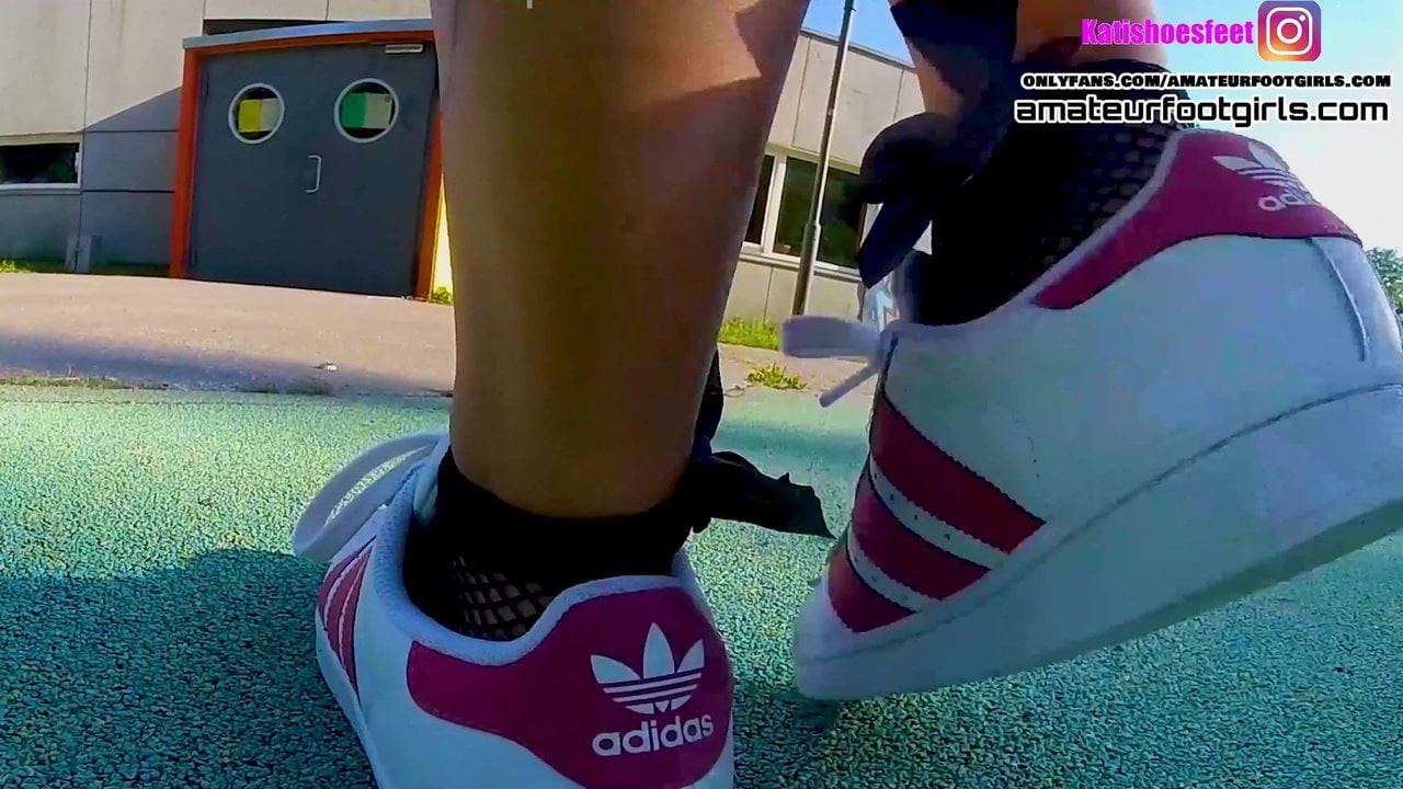 Kırmızı adidas süperstarları giyen kız ayakkabıcılık yapıyor, file çoraplara daldırıyor