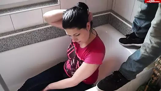 Giysili bir kız banyoda oturur ve bir dere alır.